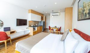 Cet appartement comprend une chambre avec un grand lit blanc et une cuisine. dans l'établissement HSuites Hotel and Apartment, à Đà Nẵng
