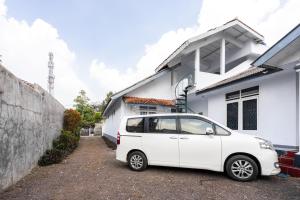 um carro branco estacionado em frente a uma casa branca em RedDoorz Syariah near RSUD Cimacan em Bogor