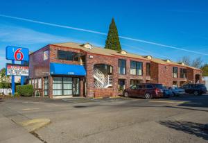 un edificio de ladrillo con coches estacionados frente a él en Motel 6-Canby, OR, en Canby