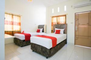 two beds in a hotel room with red and white at RedDoorz @ Pematangsiantar 2 in Pematangsiantar