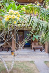 a tree with yellow flowers in front of a building at Asoka Homestay in Senggigi 