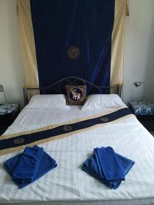 a bed with two blue towels on top of it at Bellmans Restaurant & Guesthouse in Karon Beach