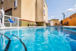 ein großer blauer Pool mit Stühlen und ein Gebäude in der Unterkunft Econo Lodge in Valdosta