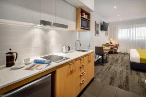 a kitchen with a sink and a bed in a room at Quest Bella Vista in Baulkham Hills