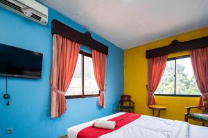 a bedroom with a bed and two windows at RedDoorz near Istana Bogor in Bogor