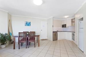 a kitchen with a table, chairs and a refrigerator at Langley Park Apartments in Maroochydore