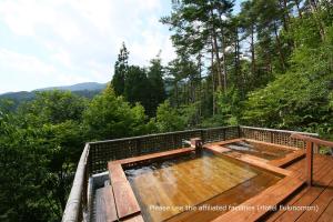 a hot tub on a deck in the woods at Tokonamiso in Nagiso