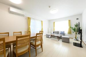 - un salon avec une table, des chaises et un canapé dans l'établissement SAKURA93, à Sapporo