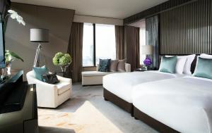 a hotel room with two beds and a couch at The Okura Prestige Bangkok in Bangkok