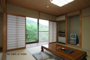 a room with a table and a tv and windows at Tokonamiso in Nagiso