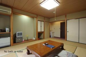 ein Wohnzimmer mit einem Tisch und einem TV in der Unterkunft Tokonamiso in Nagiso