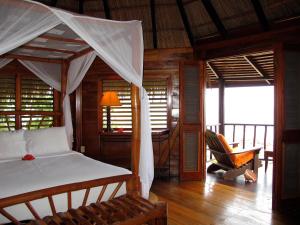a bedroom with a bed with a canopy and a balcony at Tensing Pen in Negril