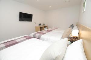 a room with three beds and a television at Line Hotel Myeongdong in Seoul