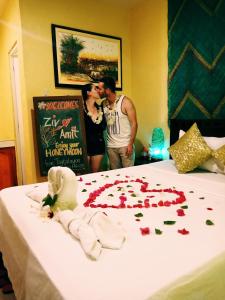 a couple kissing in front of a bed with roses on it at TAGBALAYON Lodging House in Siquijor