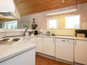 una gran cocina con armarios blancos y techos de madera. en 8 person holiday home in Hj rring, en Hjørring
