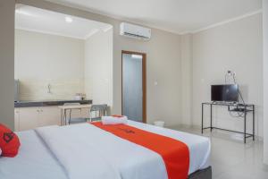 een slaapkamer met een groot wit bed en een oranje deken bij Residences by RedDoorz near MT Haryono - Minimum Stay 7 Days in Jakarta