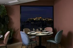 a dining room with a table and chairs and a large window at Evripides Hotel in Athens