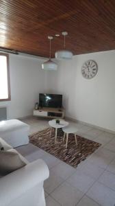 a living room with a table and a clock on the wall at Charmante Maison dans petite citée de caractère 13km du ZOO in Luché-Pringé