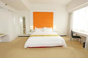 um quarto com uma grande cama branca e uma secretária em Borneo Royale Hotel em Tawau