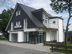 un bâtiment blanc et noir avec un toit noir dans l'établissement Pension Haus Astenblick, à Winterberg