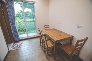 a wooden table and chairs in a room with a window at Hakka Eco-farm 雅歌園民宿食農教育有機農場 in Wanluan