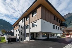 a building in a parking lot with mountains in the background at A Casa Elegance in Längenfeld