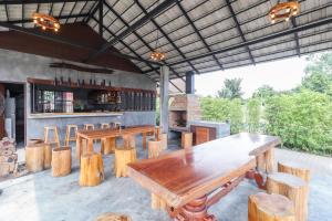 un patio avec des tables et des chaises en bois ainsi qu'un bar dans l'établissement Relax Garden House, à Chiang Mai