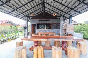 a large wooden table and some wooden logs at Relax Garden House in Chiang Mai