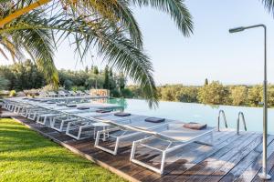 uma fila de espreguiçadeiras numa doca ao lado de uma piscina em Hotel Mas Lazuli em Pau