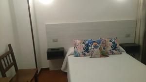 a bedroom with a bed with a pillow and a chair at Hostal Fisterra in Lugo