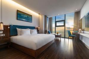 A bed or beds in a room at Maximilan Danang Beach Hotel