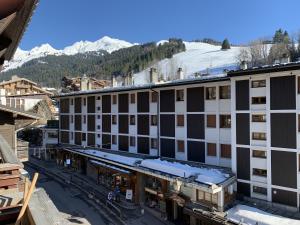 an apartment building with a snow covered mountain in the background at Candia 5 - Appartement en duplex dans le centre in La Clusaz