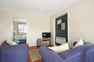 a living room with two blue chairs and a tv at Carmens Inn in Scamander