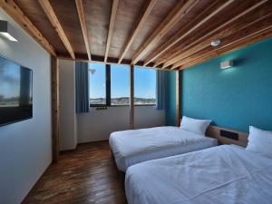 Cette chambre comprend deux lits et une grande fenêtre. dans l'établissement CABIN&HOTEL ReTIME, à Naha