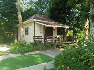 una pequeña casa blanca con un banco en un jardín en Wasuthan Garden House en Nong Khai