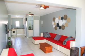 a living room with a red couch and a kitchen at 28 and 29 The Bridge in St Lucia