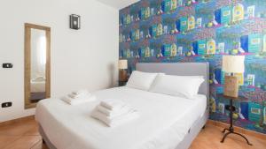 a bedroom with a white bed with a colorful wall at Italianway - Ottoventi Apartments in Lampedusa