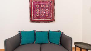 a couch with blue pillows and a rug on a wall at Italianway - Ottoventi Apartments in Lampedusa