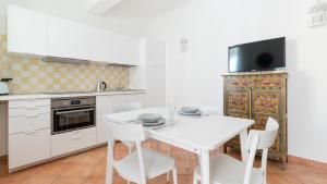 a white kitchen with a white table and chairs at Italianway - Ottoventi Apartments in Lampedusa