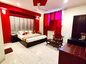 sypialnia z czerwonymi ścianami, łóżkiem i krzesłem w obiekcie Hotel Unistar w Nowym Delhi