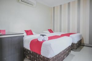占碑市RedDoorz Syariah near Jamtos Jambi 2的酒店房间里的两张床上有毛巾