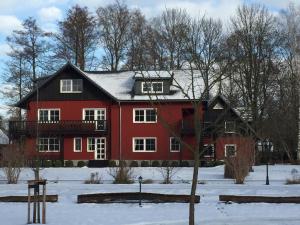 una casa rossa con un tetto nero nella neve di Ferienhof Spreewaldromantik a Burg