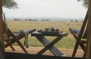 une table sur une terrasse avec vue sur un champ dans l'établissement Cherero Camp, à Serengeti