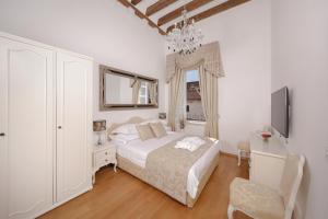 a white bedroom with a bed and a tv at Palmotta Palace in Dubrovnik