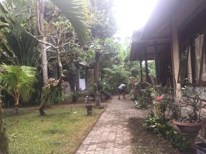 a person walking down a path in a garden at Batan Duren House in Ubud