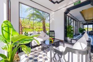 a living room with a table and chairs and plants at Fivitel Hoi An Hotel in Hoi An