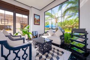 a living room with white furniture and large windows at Fivitel Hoi An Hotel in Hoi An