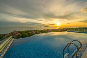 a swimming pool with a sunset in the background at Fivitel Hoi An Hotel in Hoi An