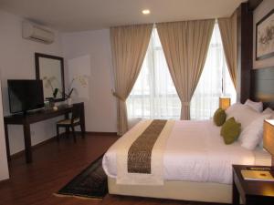 a bedroom with a large bed with a desk and windows at Samsuria Beach Resort & Residence in Cherating