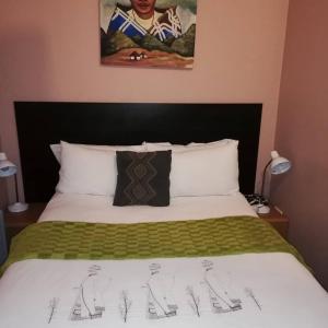 - une chambre dotée d'un lit avec une couverture verte et blanche dans l'établissement Flossie B&B, à Pimville